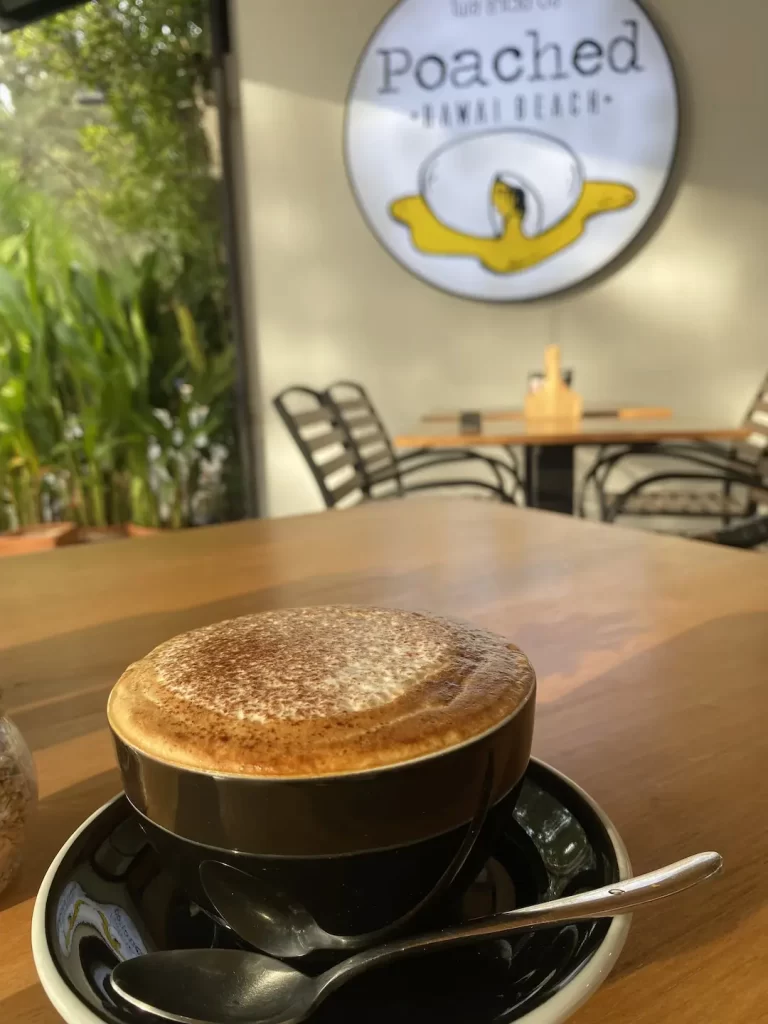 Frothy cappuccino in the morning sun in front of our poached sign at one of the most instagrammable spots near nai harn: Poached Breakfast Cafe Rawai, Phuket, Thailand